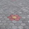 Bahçede kullanılmış, farklı renklerde altıgen parke taşları ile oluşturulmuş çiçek deseni.