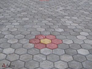 Bahçede kullanılmış, farklı renklerde altıgen parke taşları ile oluşturulmuş çiçek deseni.