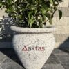50x50x50 cm boyutlarında, beyaz mozaik dokulu vazo şeklinde beton saksı içinde yeşil yapraklı bir bitki ile dış mekanda kullanılmış hali.