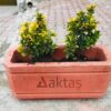 Dikdörtgen-Beton-Saksi-Kirmizi-80x30x40-Aktaş 80x30x40 cm boyutlarında, üzerinde Aktaş logosu bulunan canlı kırmızı renkte dikdörtgen beton saksı. İçinde sarı-yeşil yapraklı bitkilerle dolu, dış mekanda (kaldırımda) kullanılmış hali.